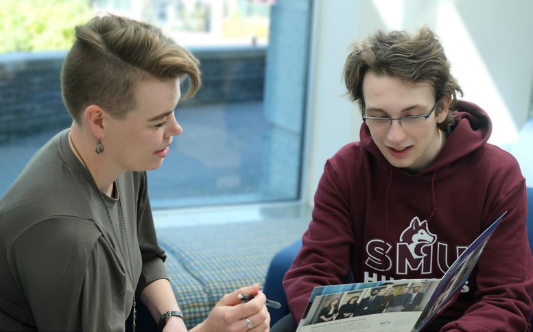 An Advisor helping a student look through a viewbook.